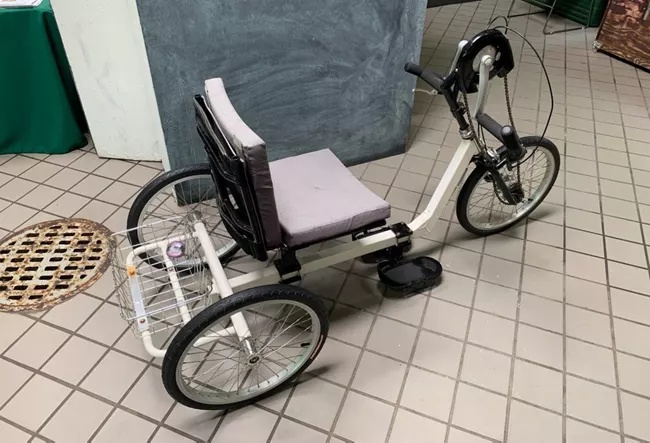 a black and gray tricycle for adults that is operated with hand pedals.