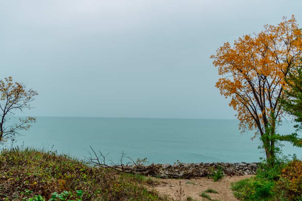 a grassy sand dune sits in front of the blue waters of Lake Michigan at Indiana Sand Dunes National Park