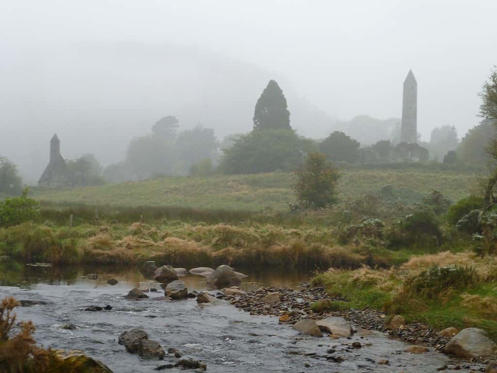 A misty morning in accessible Ireland.  A stream is in the foreground and in the mist are the remains of an old church