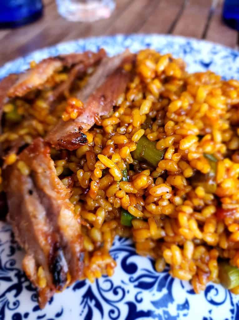 a blue and white plate holds steak paella, a local food that is great to try on a wheelchair accessible cruise to Europe