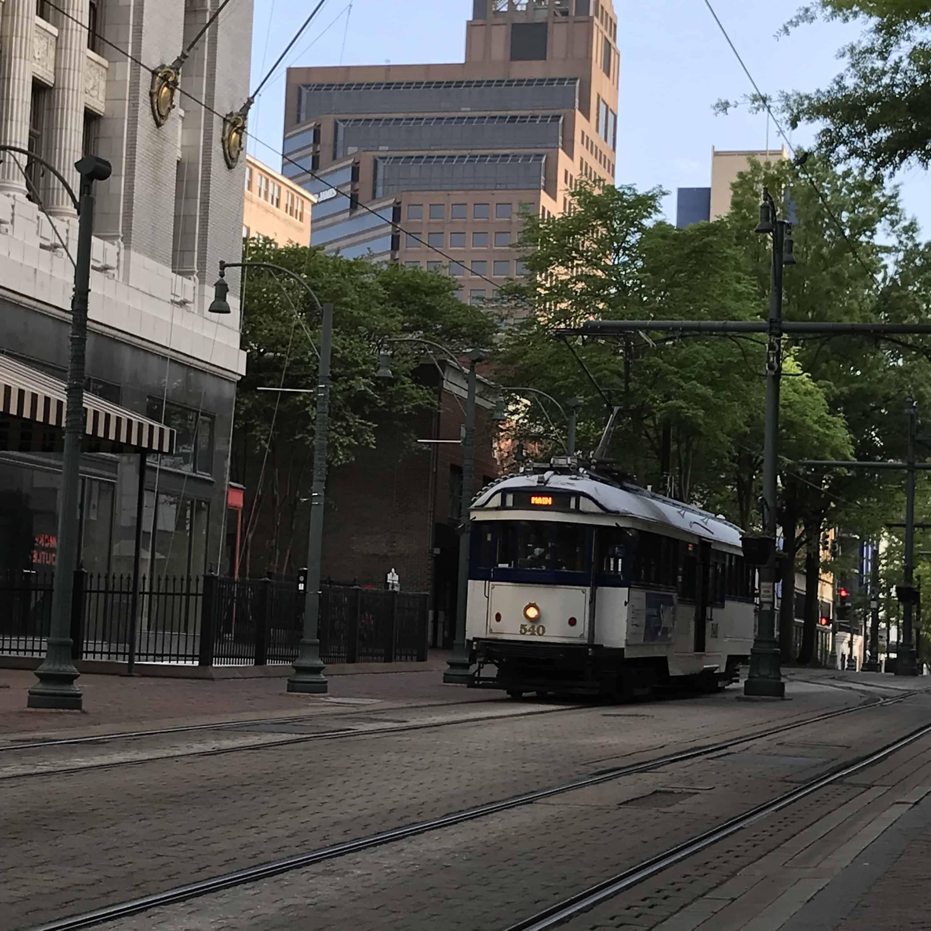 a white trolley enters from the right as it goes down a paved main street in Memphis