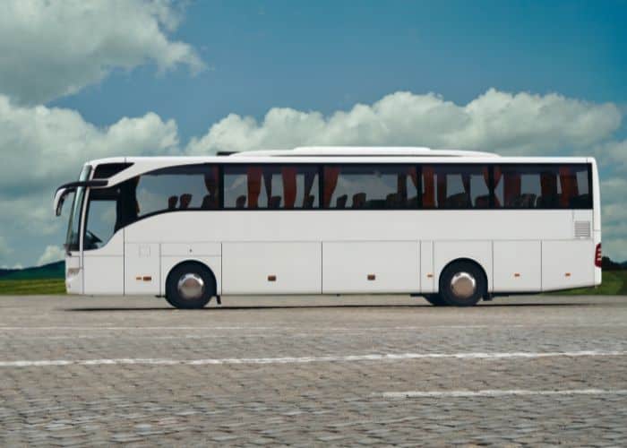 a white shuttle bus sits in an open parking lot.  Not all transportation to town will be accessible during your wheelchair accessible cruise to Europe