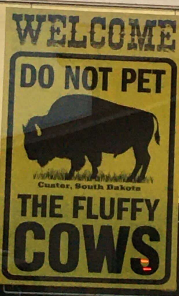 a yellow sign with black lettering has a picture of a buffalo on it and says "welcome, do not pet the fluffy cows" When planning a trip to the national parks, it's important to respect the wildlife