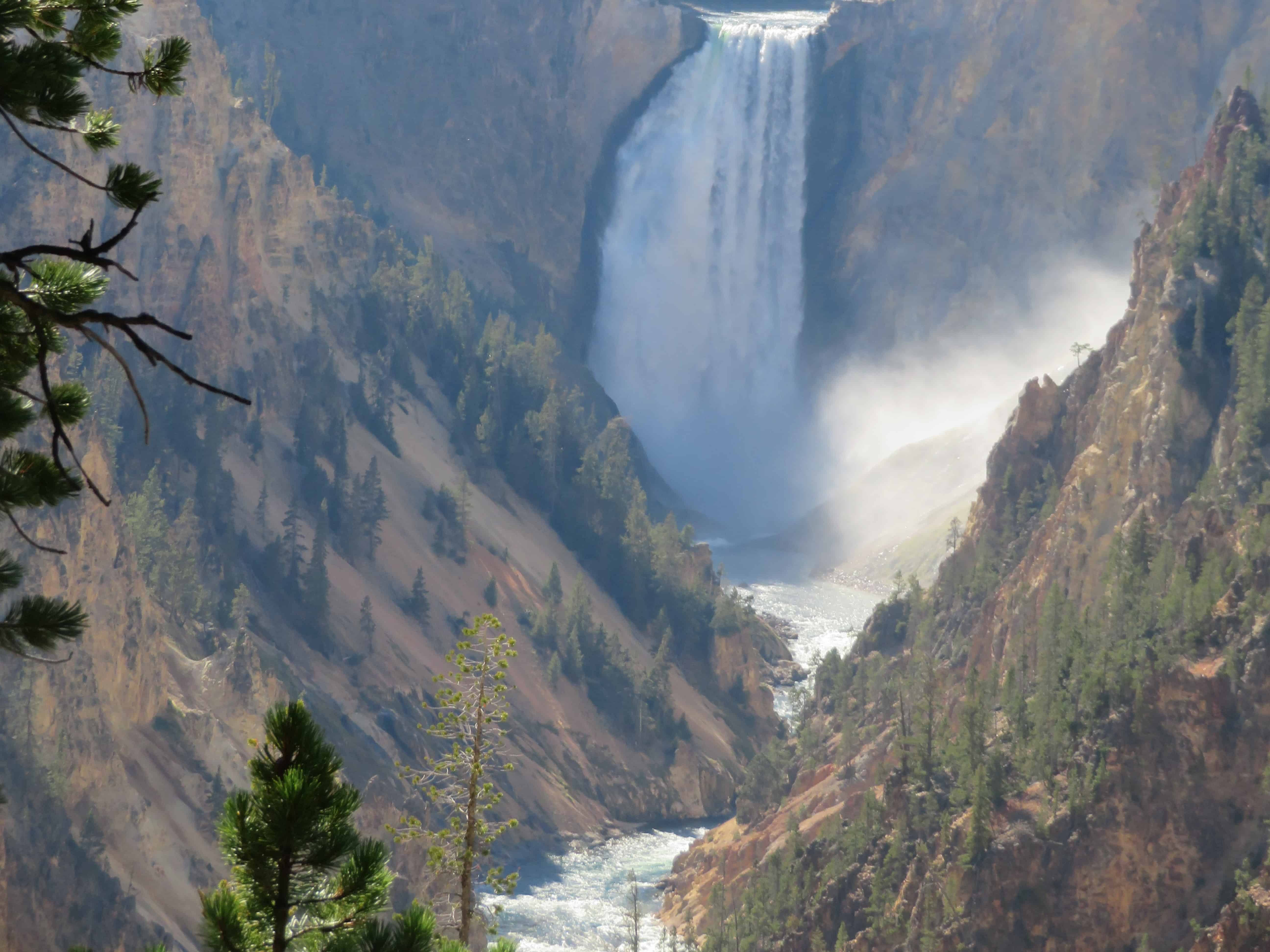 a waterfall flows over a canyon in Yellowstone National Park.  Make a list of things you want to do when planning a trip to the national parks