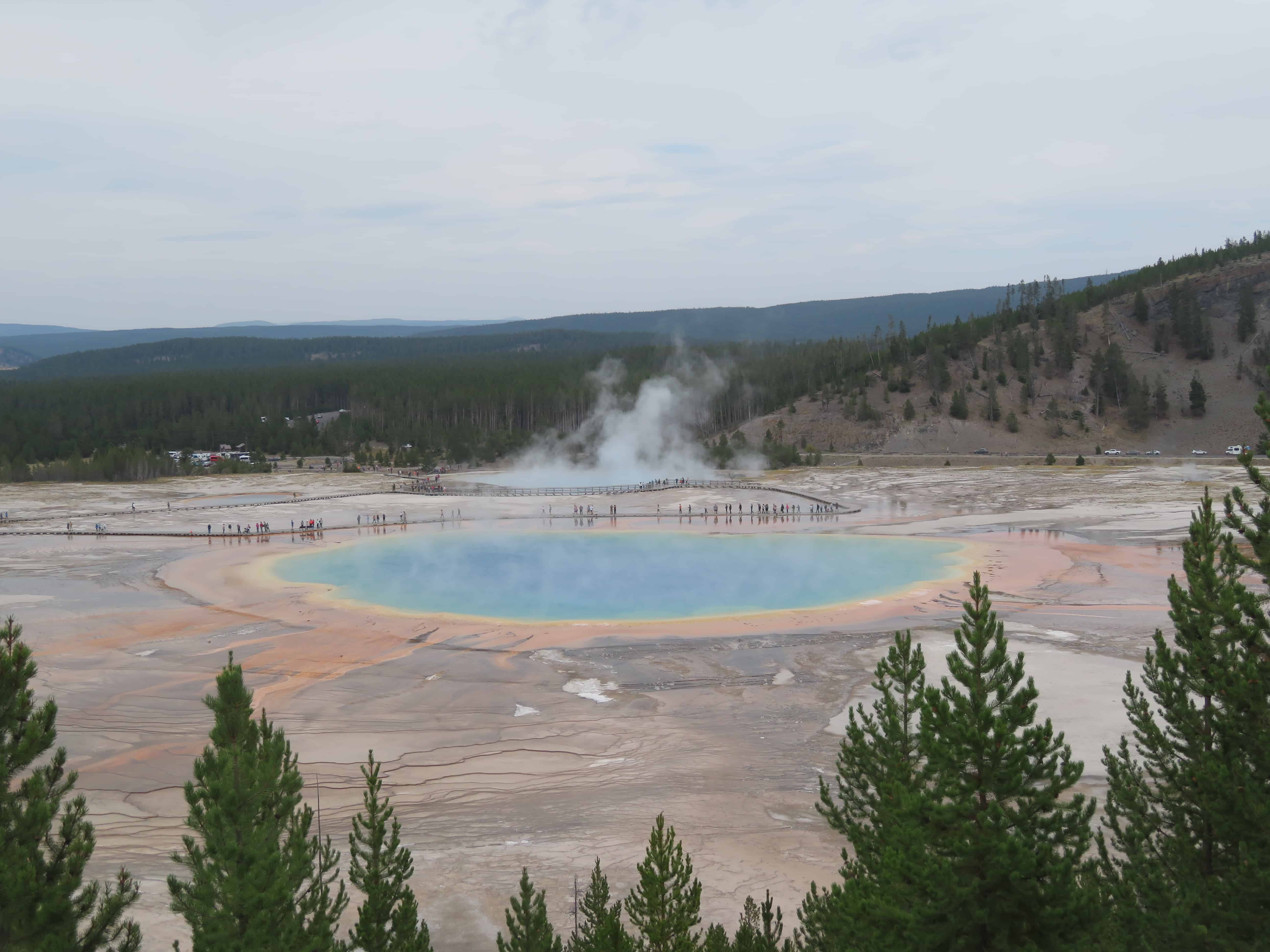 Grand Prismatic Spring is a hot spring in Yellowstone National Park that is multicolored with the center being blue and the edges of the circle yellow and orange