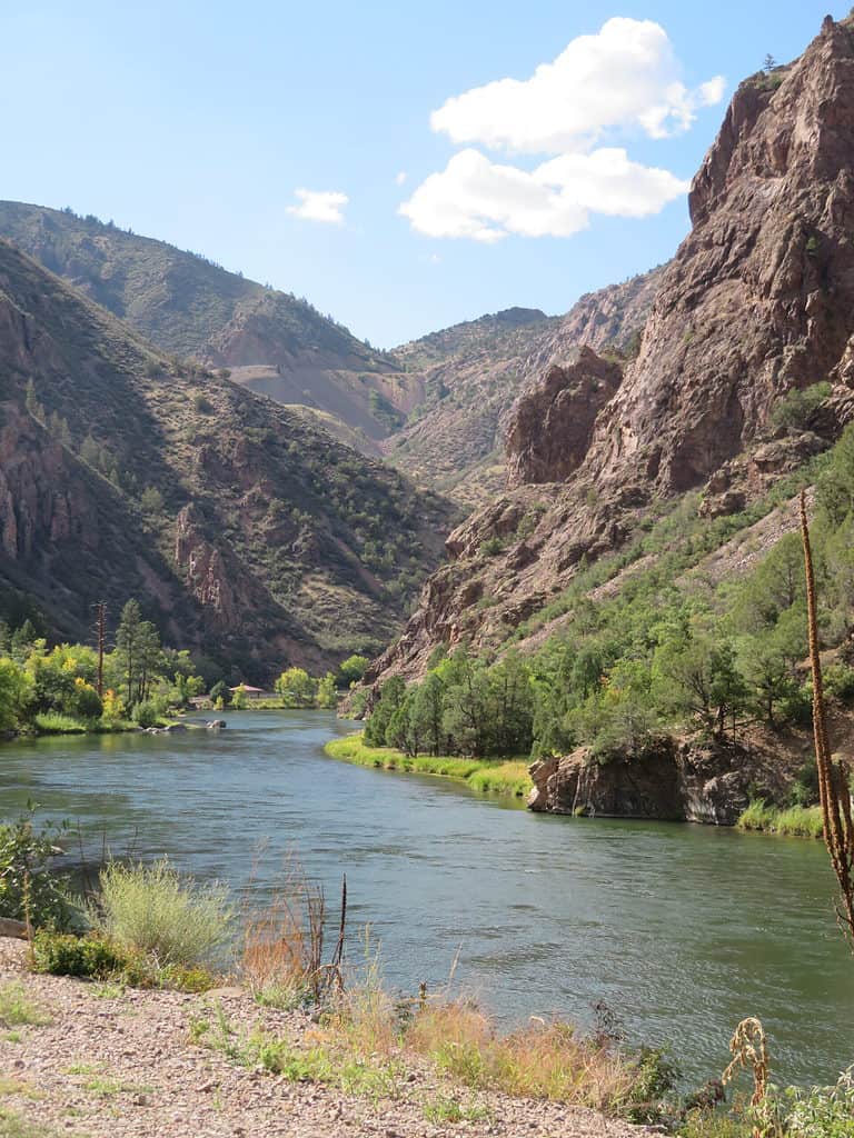 the blue colored Colorado river winds along the bottom of Black Canyon of the Gunnison in Colorado