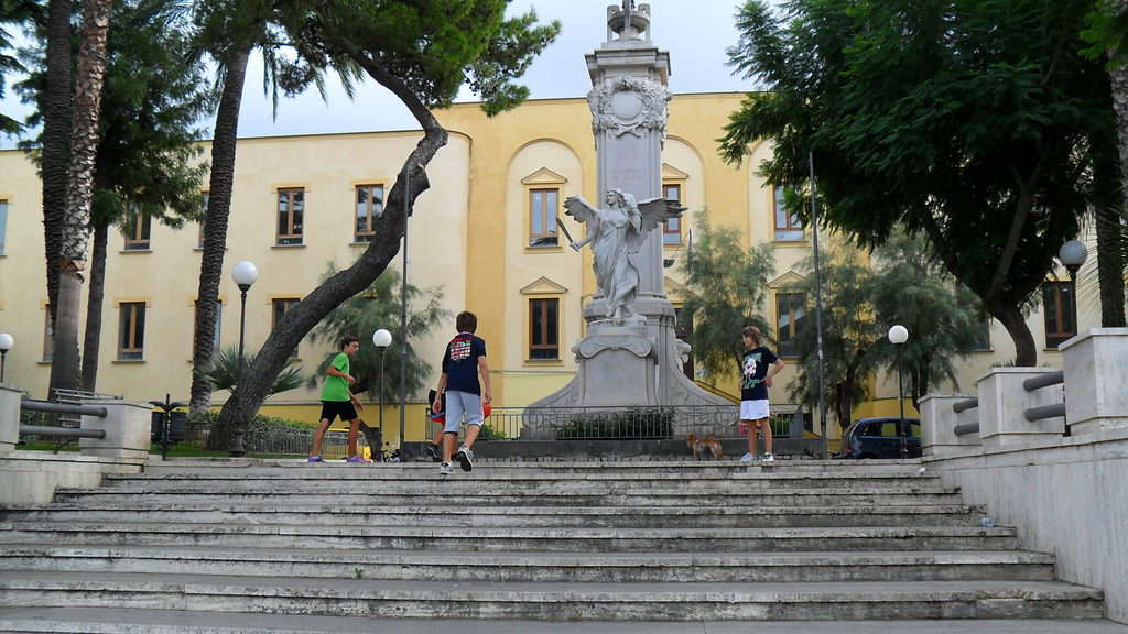 Yellow buildings are at the top of a stone stairway.  A statue sits in front of the buildings in Sorrento.  Sorrento is your last stop on the Rome and Amalfi Coast itinerary