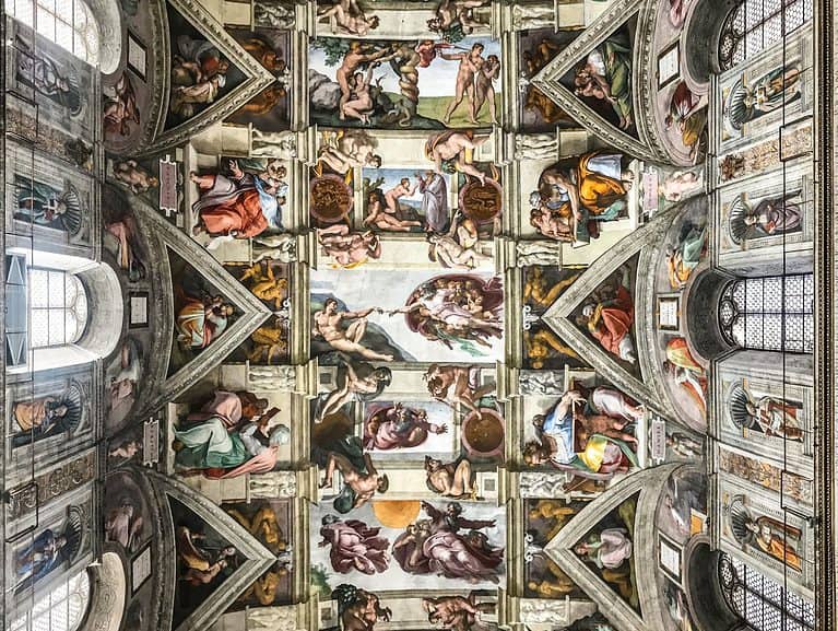 Looking up at the ceiling of the Sistine Chapel shows many intricate paintings depicting stories from the Bible