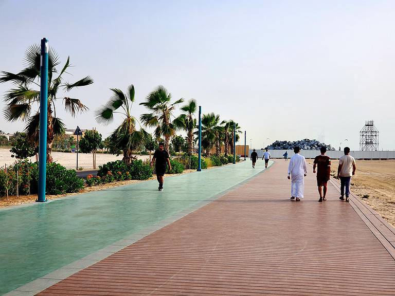 A red and green lane paved walkway is lined by palm trees in Dubai UAE