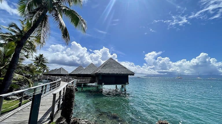 a wood boardwalk leads to over water bungalows in Tahiti