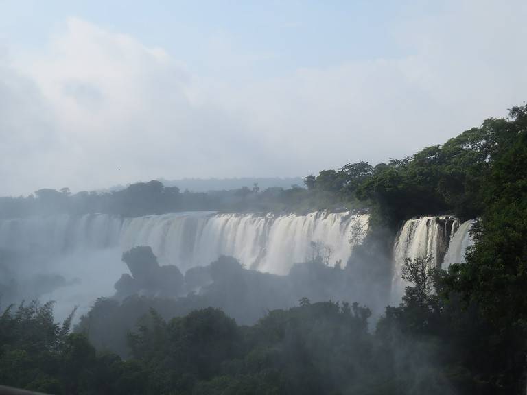 A line of waterfalls is surrounded by lush green trees at Iguazu Falls in Argentina