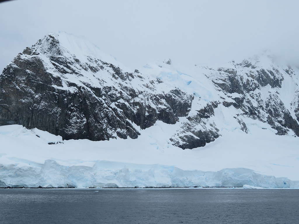 Rocky mountains emerge from a snowy glacier in Antarctica