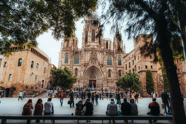 a brown cathedral sits in an open square in Barcelona Spain