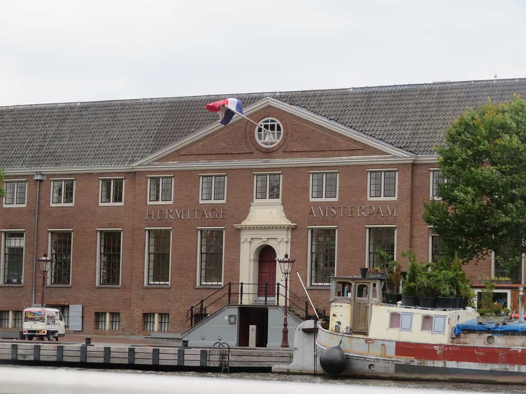 a red brick building has three stories and white windos.  An ornate white doorway is the main entrance.