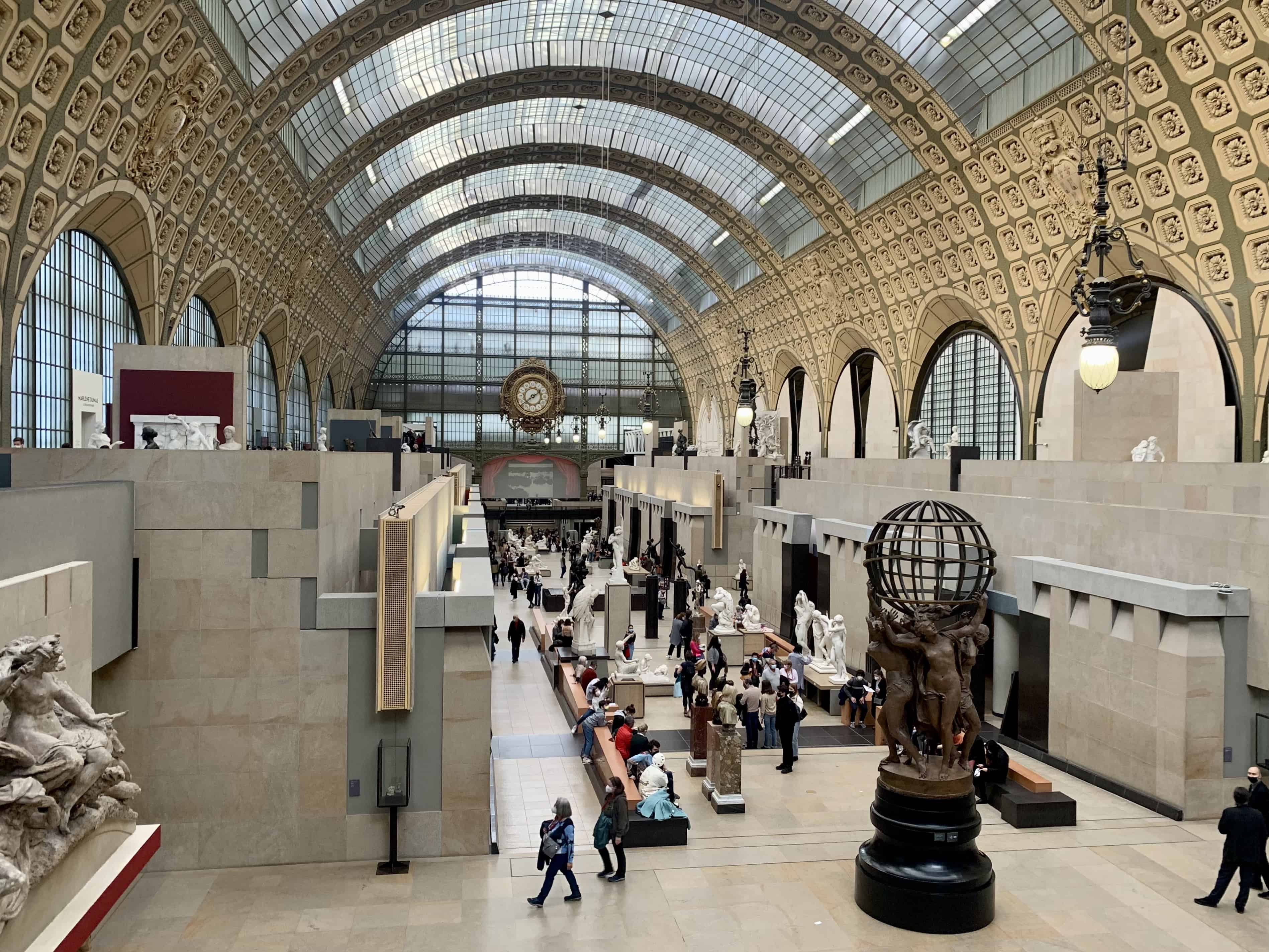 A long hall with a domed roof contains various sculptures and is part of the Musee d'Orsay in Paris.