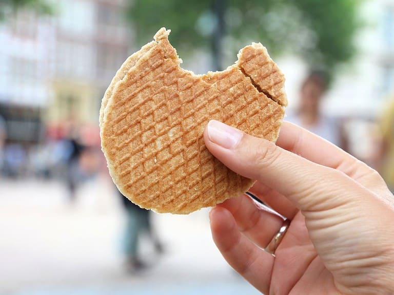 a white hand is holding a stroopwafel