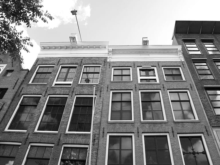 A black and white image of two three story square buildings which are known today as the Anne Frank House.