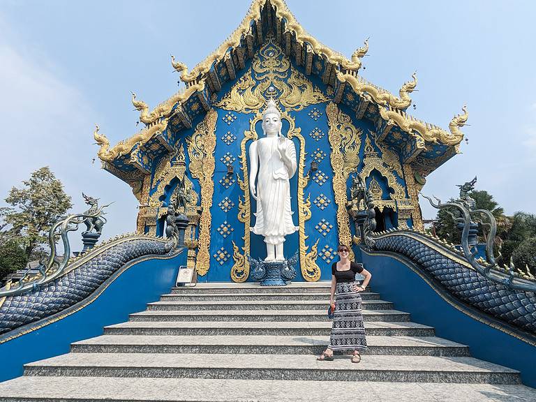 Stairs lead up to a blue and gold temple with a Budha standing in front of it.  Traveling the world can change your personality by making you more confident to go to foreign places.