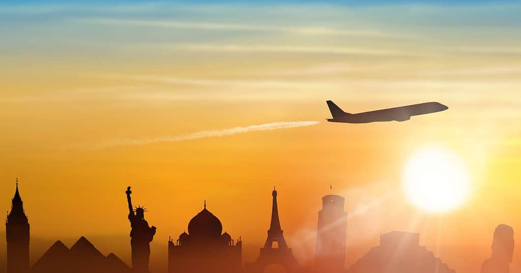 The sun is setting as a plane flies over iconic world landmarks such as the pyramids, statue of liberty and more