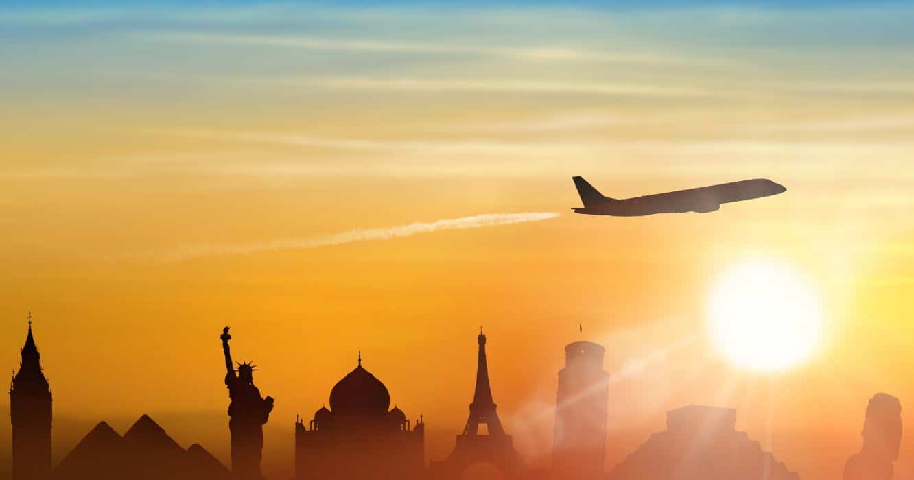 The sun is setting as a plane flies over iconic world landmarks such as the pyramids, statue of liberty and more