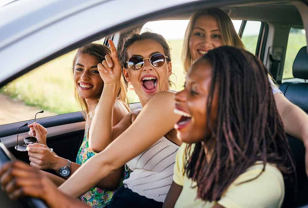 A group of girls are laughing in a car during a road trip to the national parks.