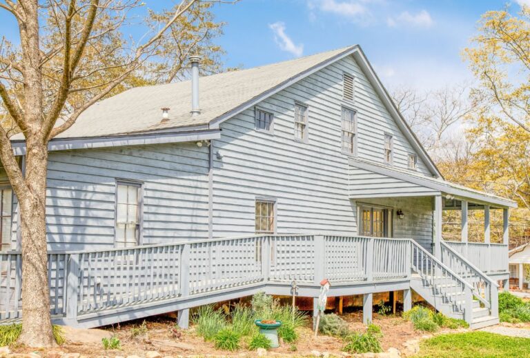 A grey house has stairs leading to the front door as well as a ramp on the left side of the house leading to the same door.