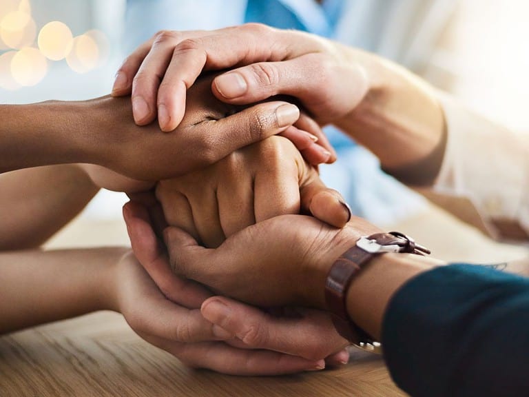 multiple hands all come together to show support.