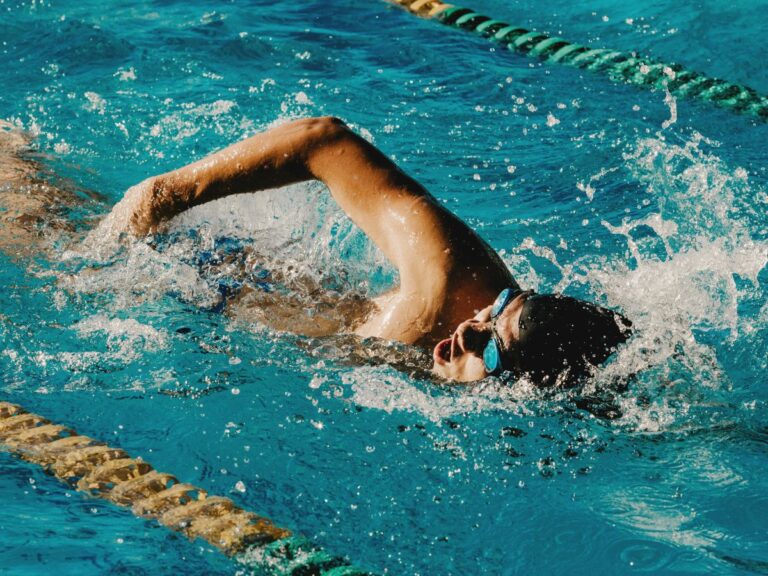 a white man with dark hair is swimming laps in a pool.  Physical activity is a common suggested coping skill for PTSD.