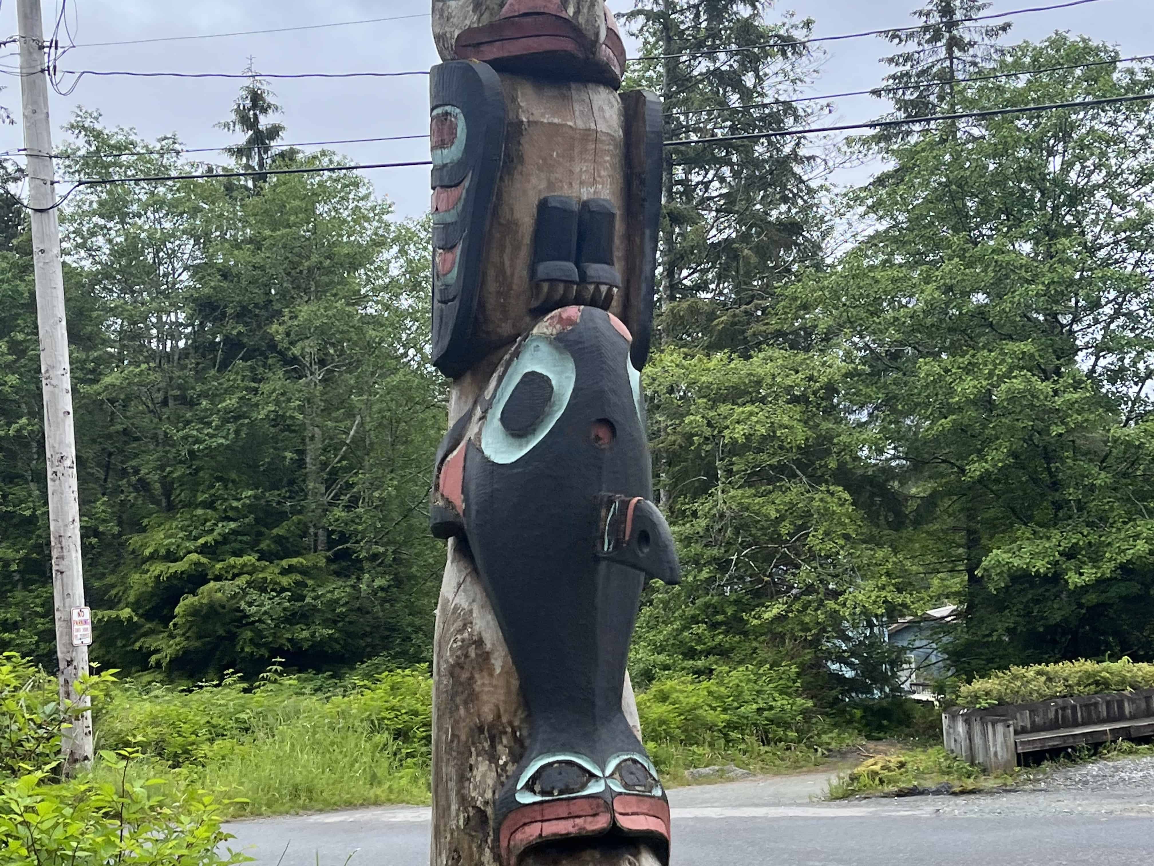 A wooden totem pole features a whale and eagle carving