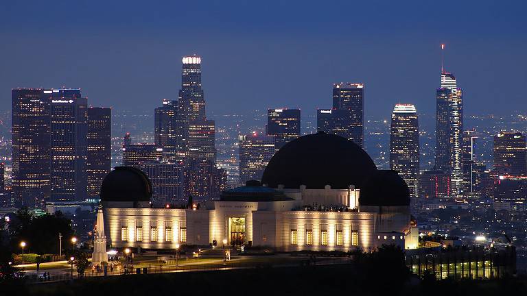 A view of the Griffith Observatory at night with the LA skyline in the background.  The Griffith Observatory is just one of the wheelchair accessible things to do in Los Angeles.