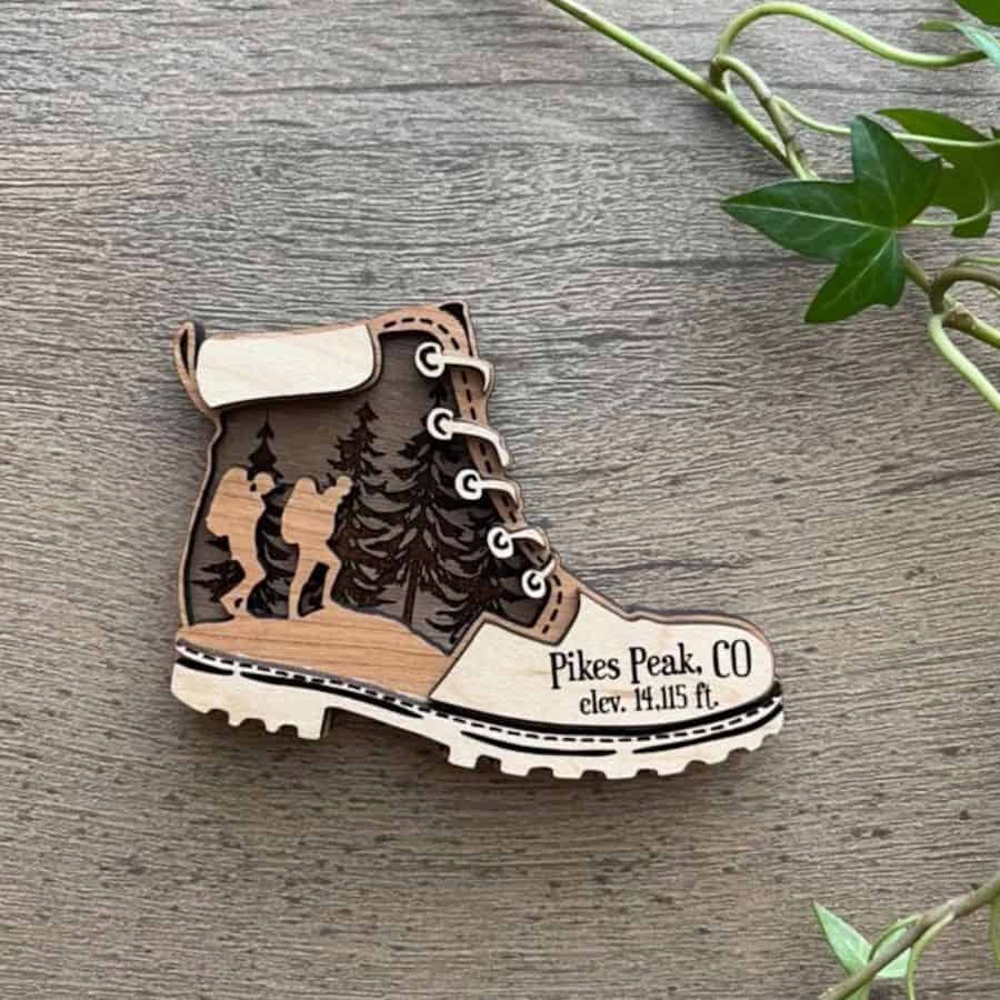 A wooden hiking boot with variuos shades of brown is a magnet that can be personalized for a specific hike and date it was taken.