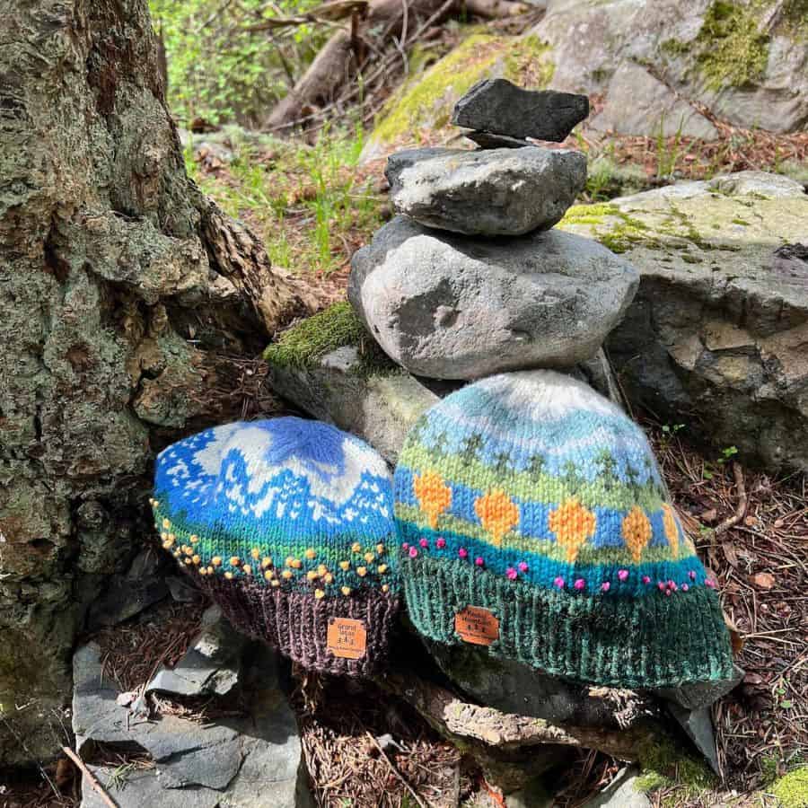 Two colorful knit hats are at the base of the tree and their design represents scenes from popular national parks.