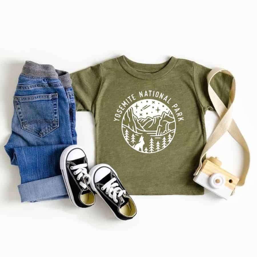 An army green t-shirt for toddlers has white lettering on it that says "Yosemite National Park" and a white circular graphic of the mountains within the park.