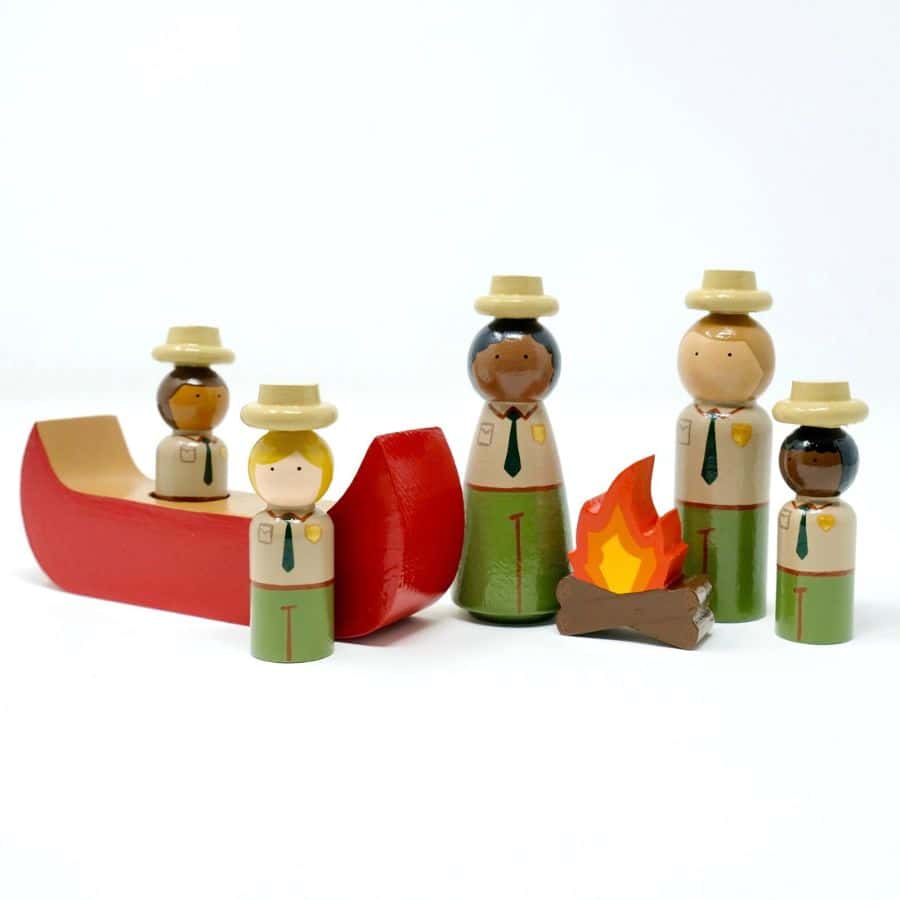 Wooden figurines depict park rangers with young children in a red wooden canoe and a campfire.  This playset is perfect for kids who love the national parks.