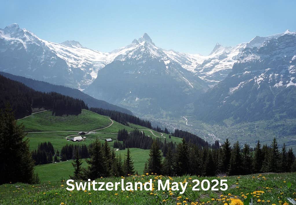 A snow capped mountain range emerges behind a green valley in wheelchair accessible Switzerland.