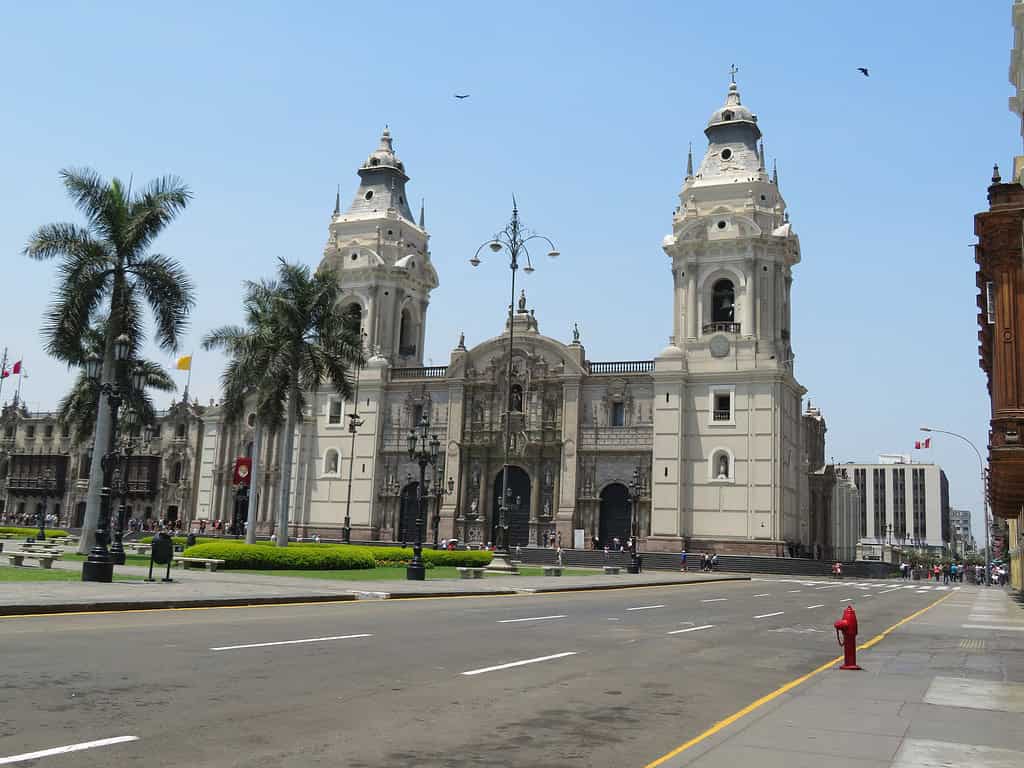 In the main square in Lima, there is a white stone building with a tower on either end in the Spanish architectural style.