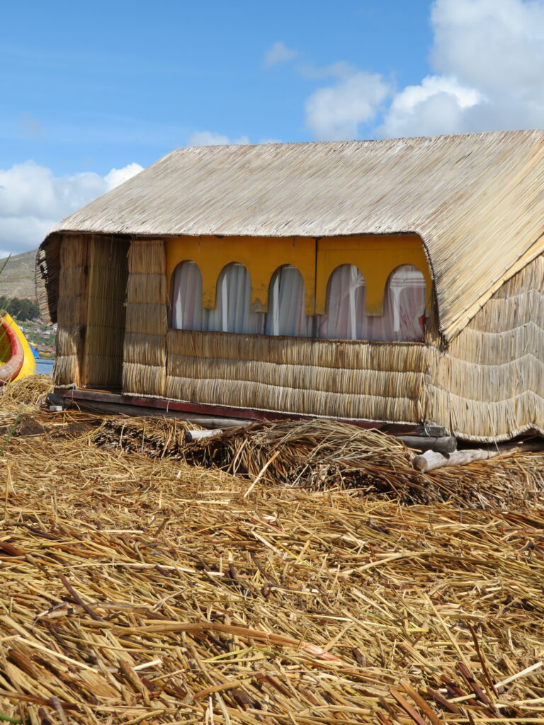 A small house made from reeds sits on a floating island, also made from reeds, in Uros on Lake Titicaca Peru.  A visit to Lake Titicaca to see these iconic idlands should be part of your 8 day Peru itinerary