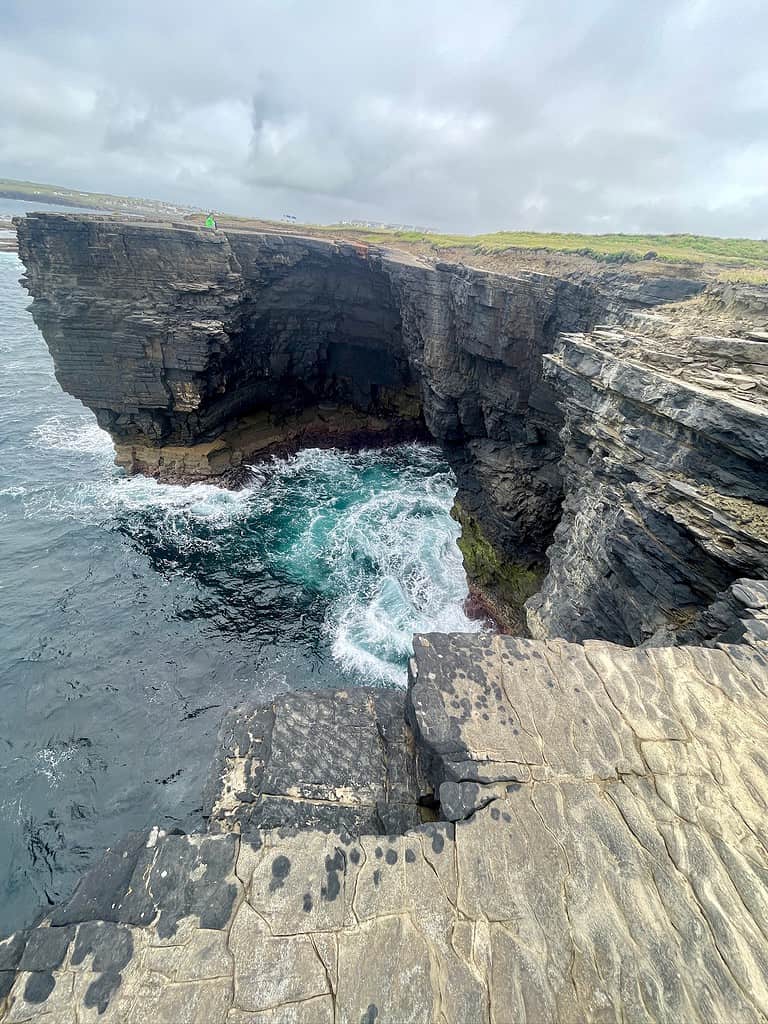 A tall stone cliff just out into the sea separate from the other cliffs that surround it.  This is part of Kilkee Cliffs which are an excellent alternative to the Cliffs of Moher.